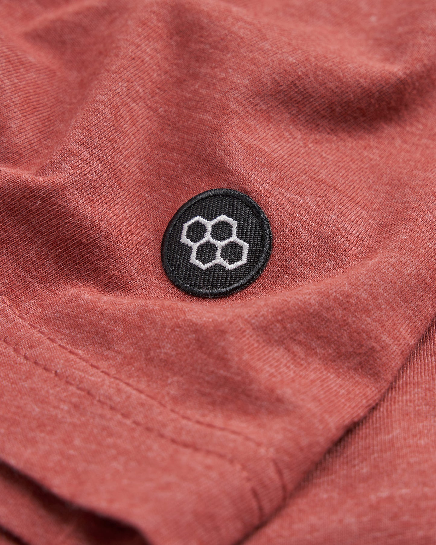 A close-up view of a textured red fabric featuring a circular black patch with a geometric design