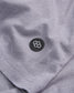 Close-up view of a gray fabric featuring a circular black patch with a geometric logo highlighting the textiles texture and seam details