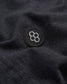 Close-up image of a black fabric featuring a circular embroidered logo with a honeycomb design