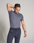 A young man in a grey t-shirt and navy sweatpants strikes a relaxed pose while adjusting his hair showcasing a stylish and casual look