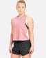 A confident woman stands in a casual athletic outfit consisting of a light pink sleeveless top and black shorts showcasing a sporty and stylish look