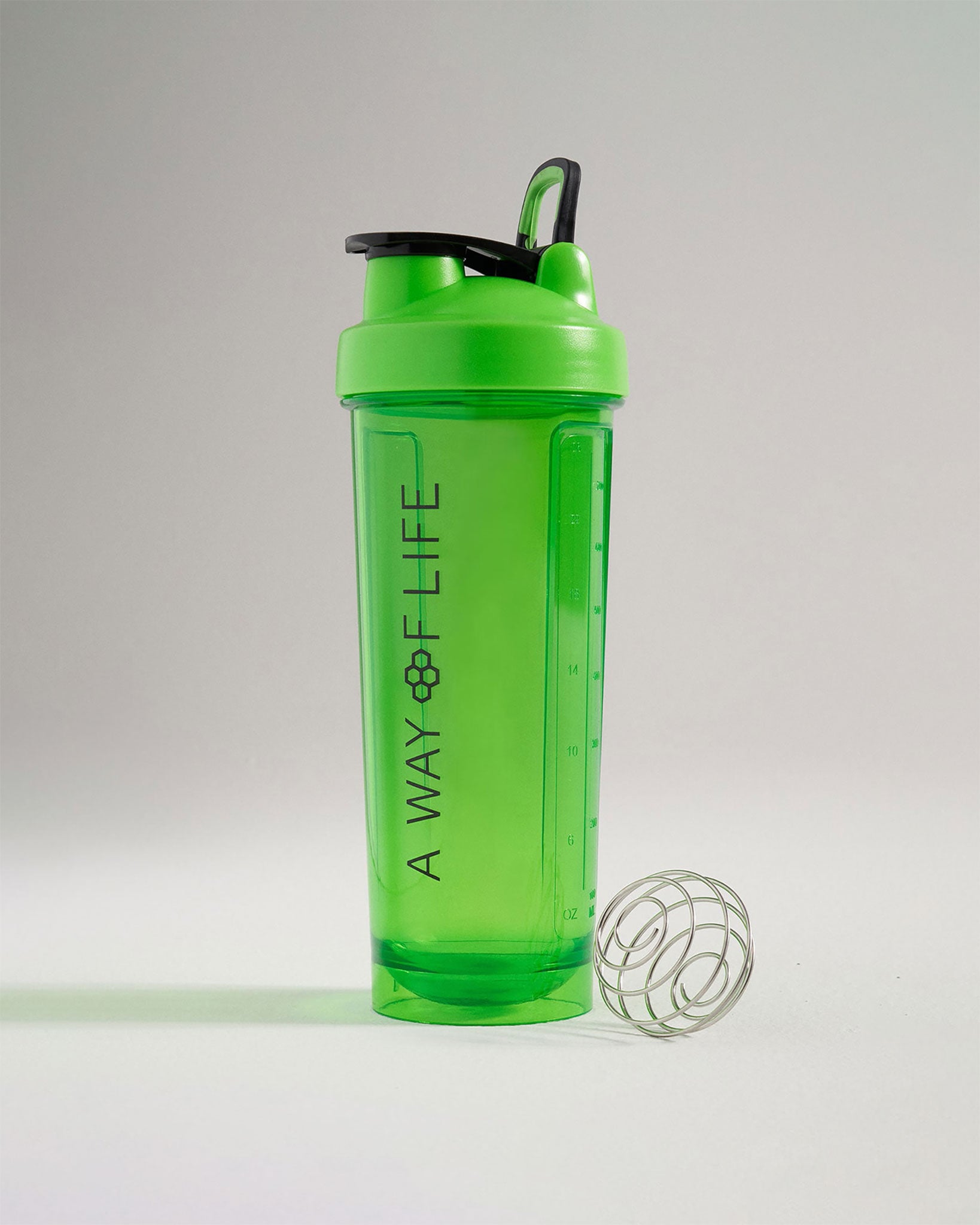 A bright green shaker bottle with a black lid featuring a measurement scale and a metal mixing ball beside it