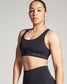 A young woman confidently poses in a sleek black sports bra and high-waisted leggings emphasizing an athletic and healthy lifestyle