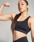 A confident woman flexing her muscular arm while wearing a black athletic top with the phrase A WAY OF LIFE printed on it