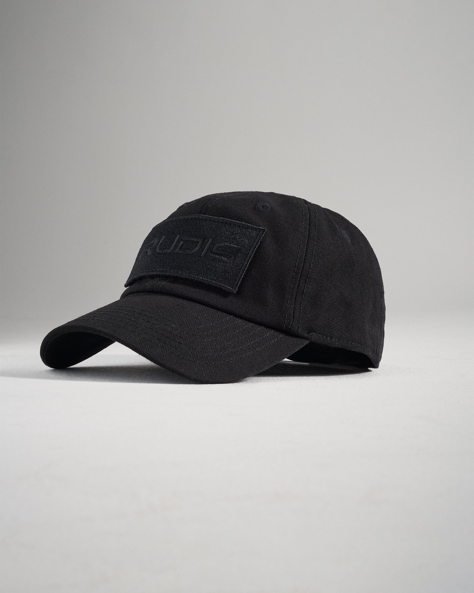 A black cap designed with a minimalist style featuring a textured patch on the front with embossed lettering and a curved brim