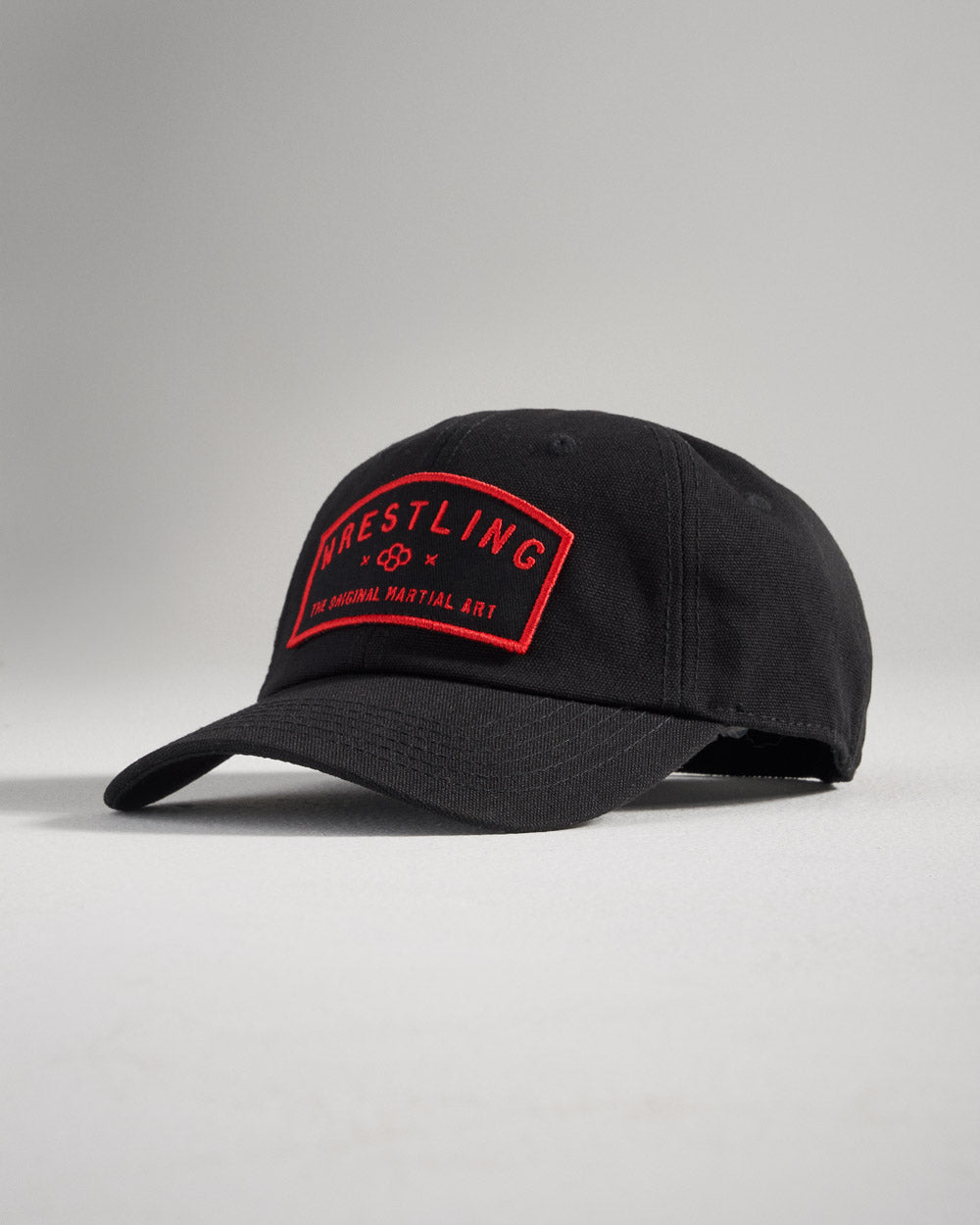 A black baseball cap featuring a bold red embroidered patch that reads WRESTLING with the tagline THE ORIGINAL MARTIAL ART