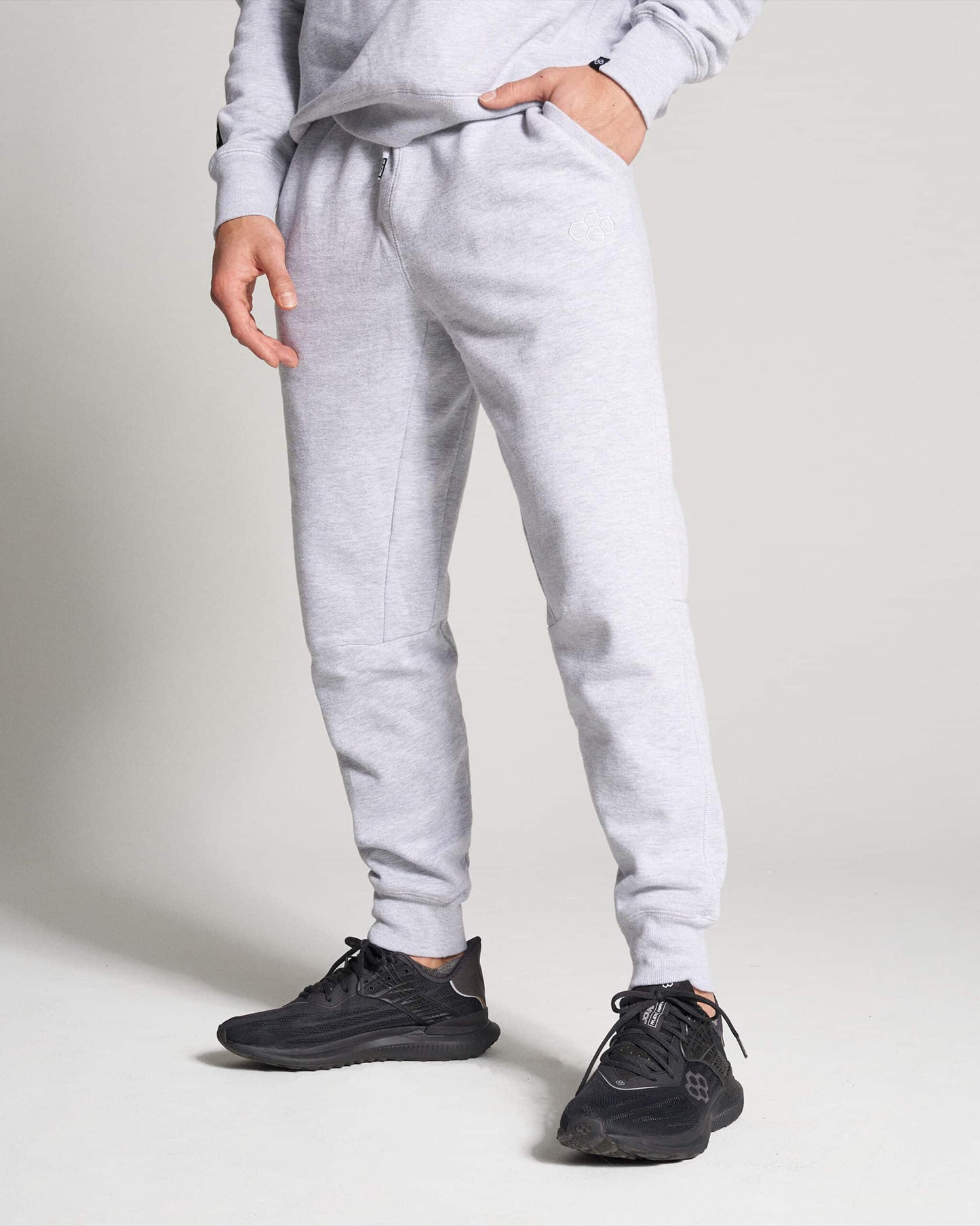 A model is dressed in comfortable grey sweatpants paired with sleek black athletic shoes showcasing a casual yet stylish look