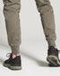 The image features a persons lower body dressed in olive green sweatpants and black athletic shoes emphasizing both comfort and style