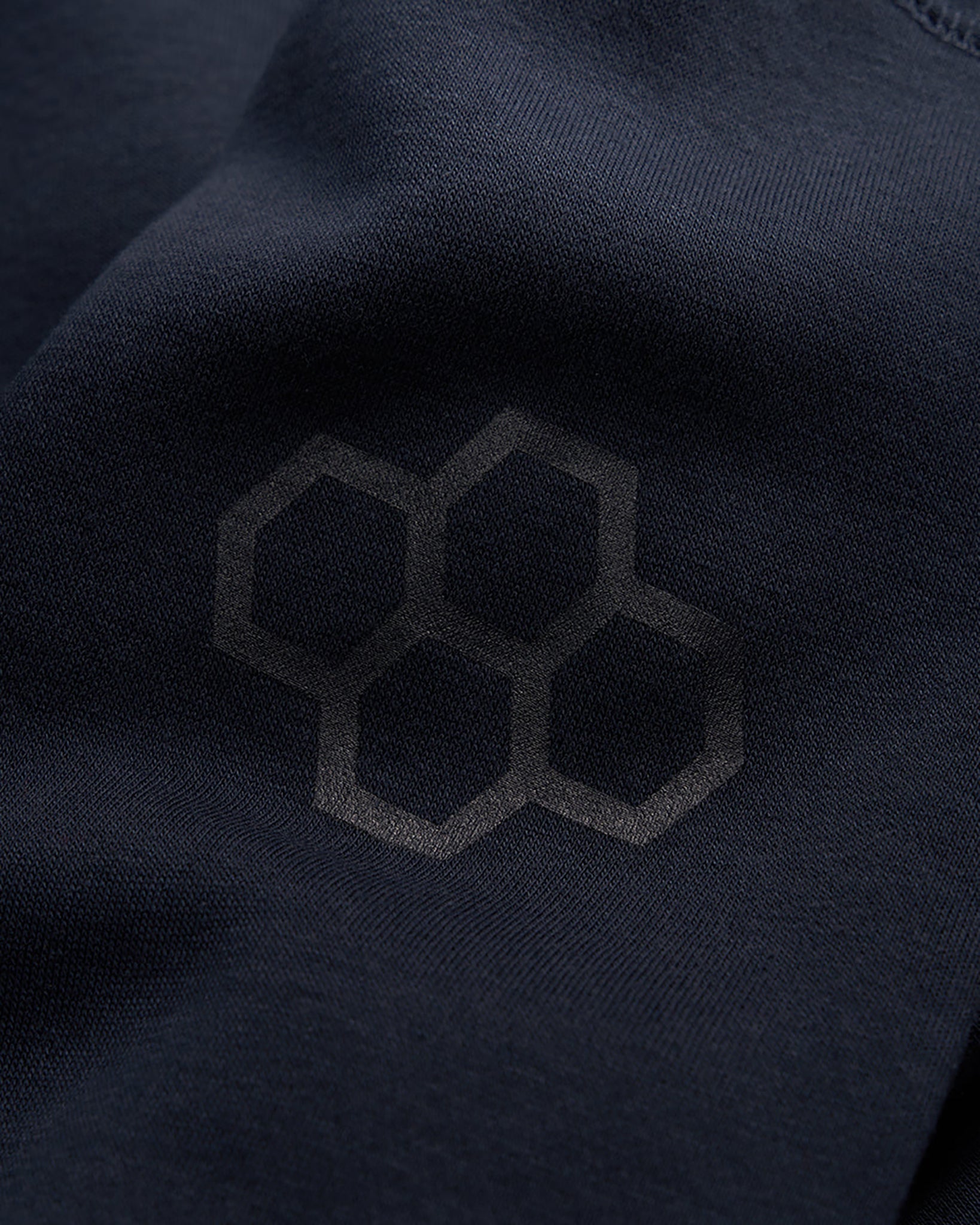 A close-up view of navy fabric featuring a subtle honeycomb pattern embedded in the material