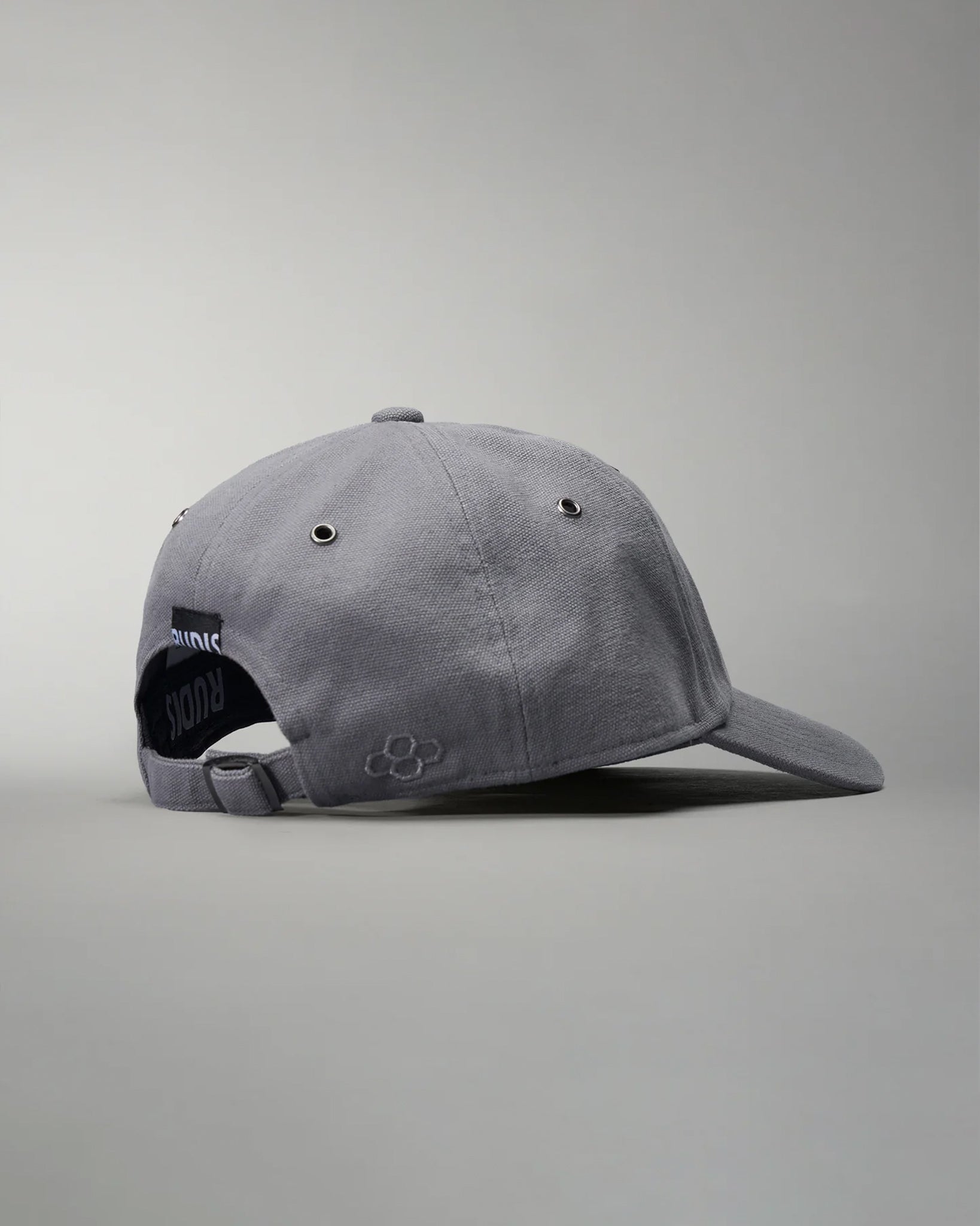 A gray baseball cap with a curved brim and adjustable strap at the back, equipped with ventilation eyelets and an embroidered logo, set against a soft gray background.