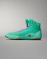 Bright turquoise high-top athletic shoe with pink laces, featuring a textured upper for grip and a durable rubber sole, against a soft gradient background.