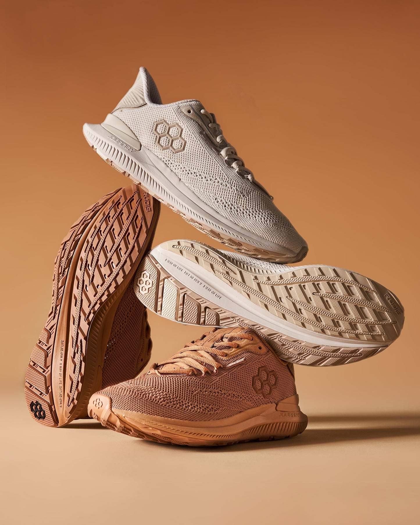 A stylish arrangement of two pairs of beige athletic shoes showcasing their innovative design and textured soles against a warm monochromatic background