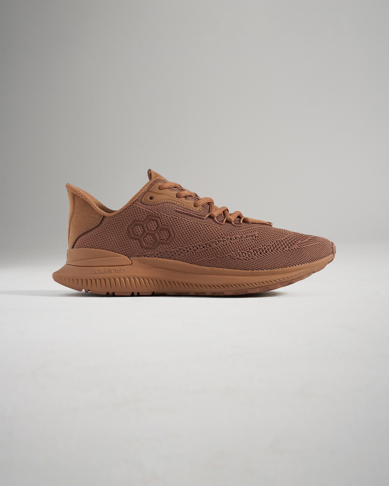 A side view of a modern brown athletic shoe featuring a breathable mesh upper sleek design elements and a textured sole for enhanced grip