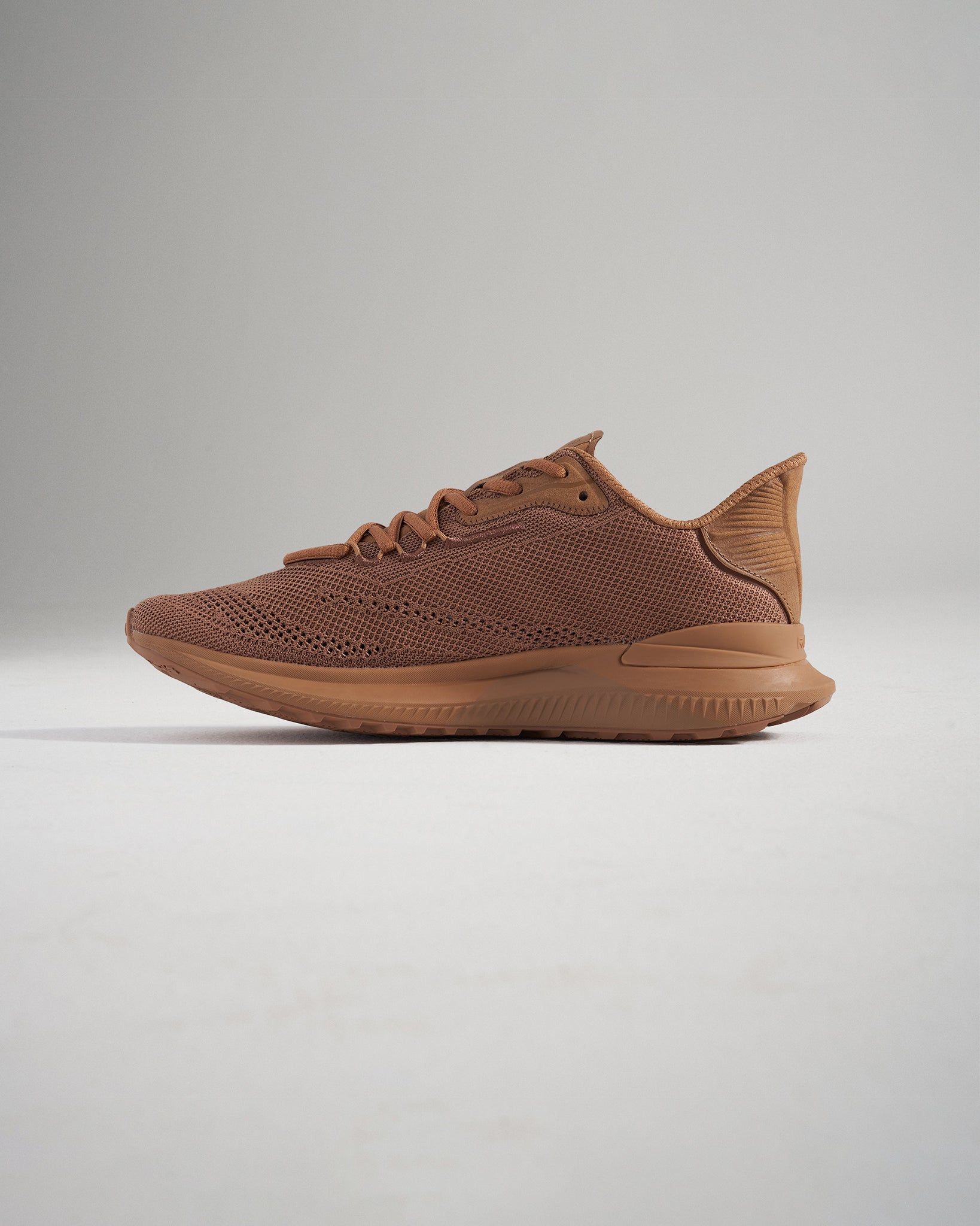 This image features a sleek brown athletic shoe with a breathable mesh upper designed for comfort and performance during various activities