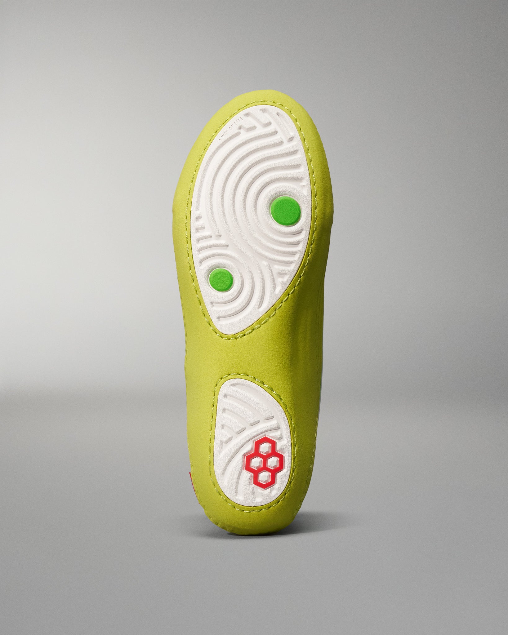 This image features the vibrant sole of a shoe showcasing a bright yellow upper with a patterned white rubber outsole and colored grip elements