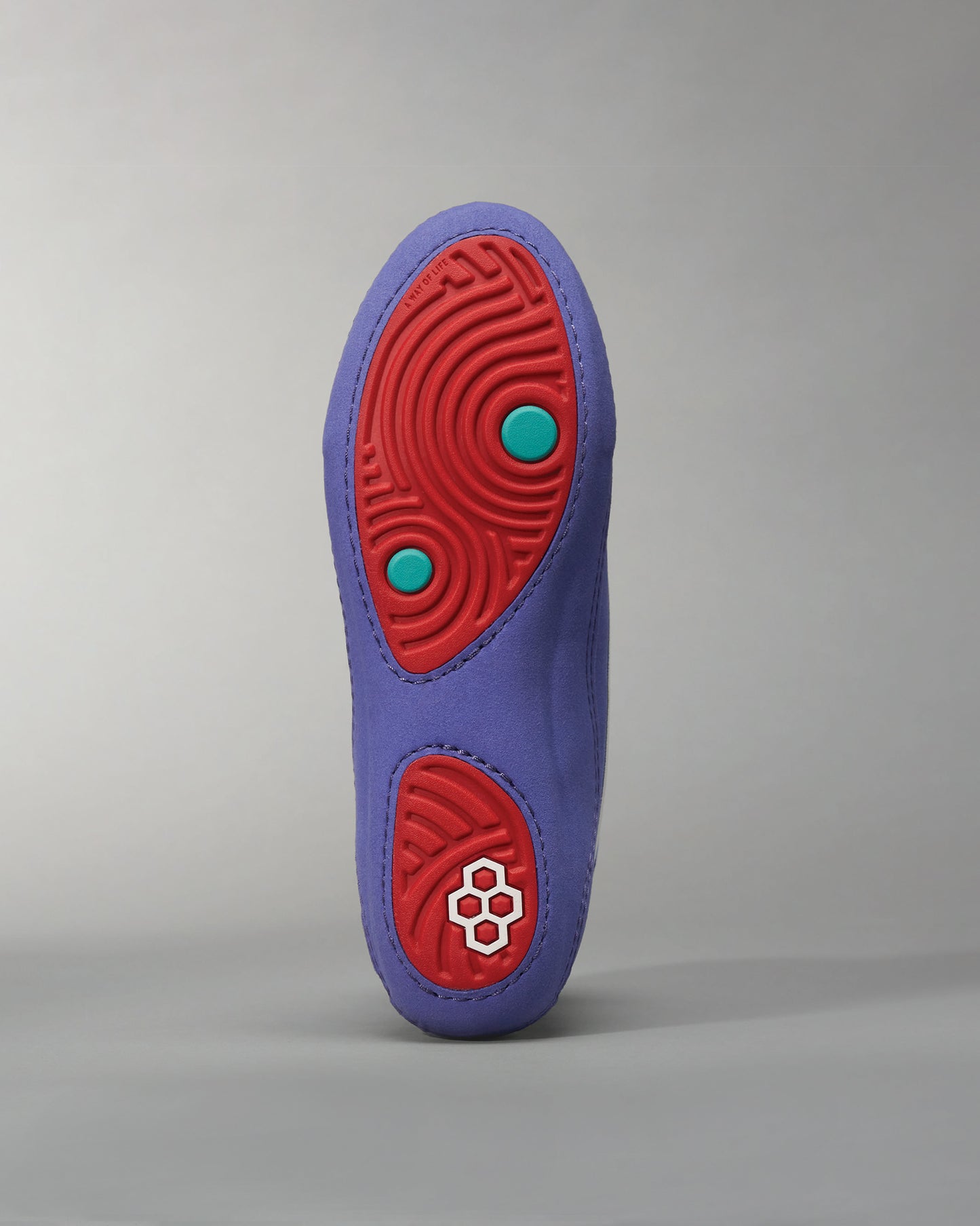 This image features the sole of a unique purple shoe with red and teal details highlighting its modern design and distinctive tread pattern