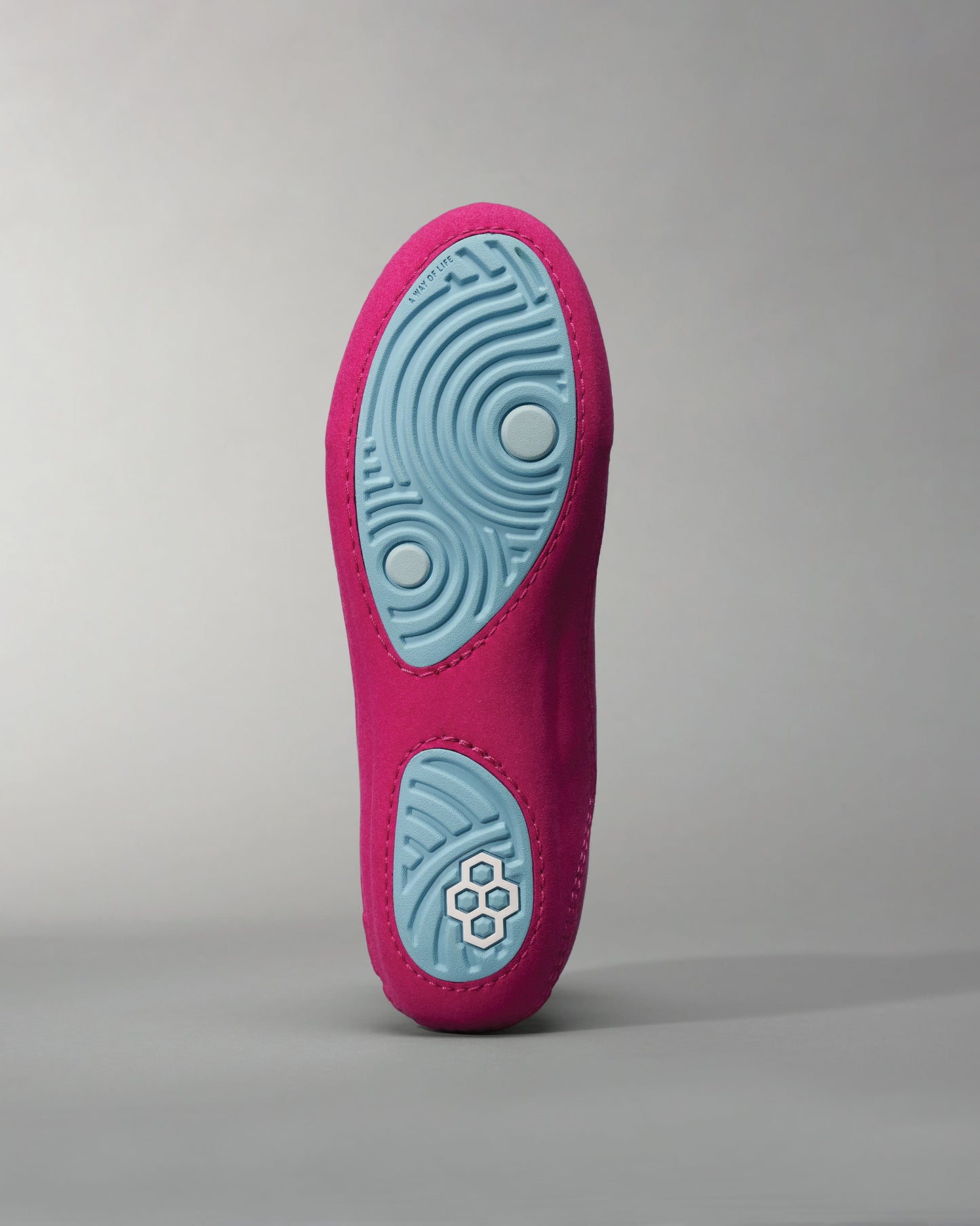 A close-up view of a vibrant pink shoe sole featuring a light blue tread design and textured grip elements