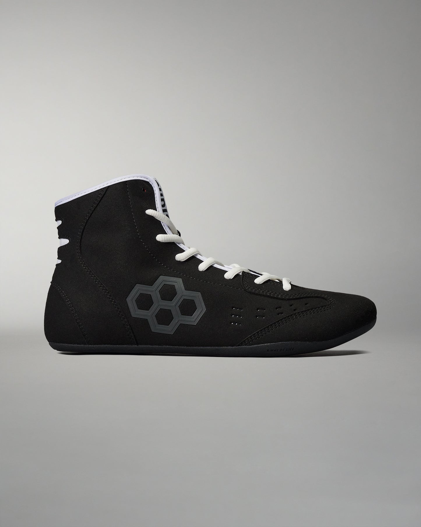 A black athletic shoe with a sleek design features a gray hexagonal pattern and white laces against a minimalist gray background.