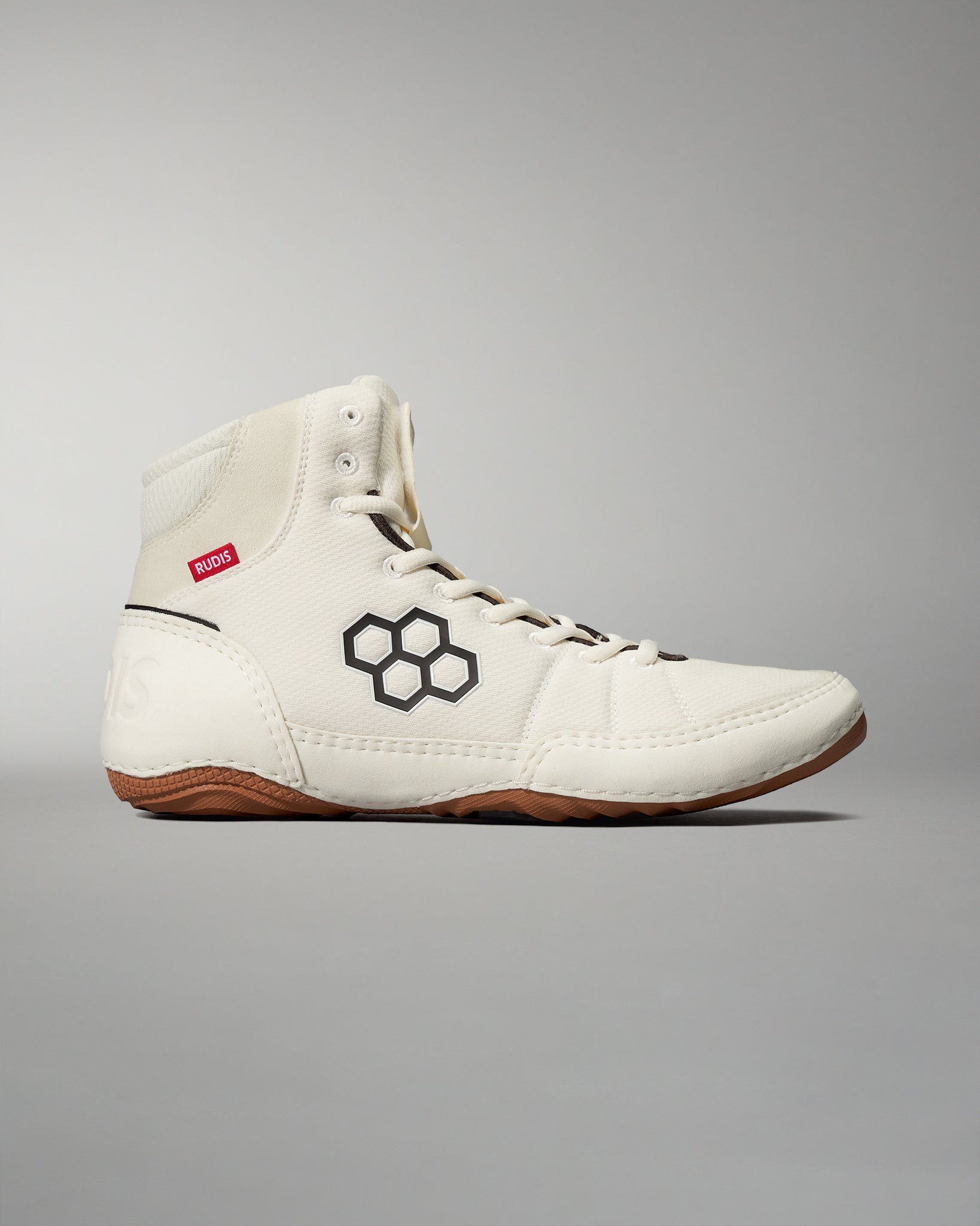 High-top wrestling shoe in cream featuring black honeycomb graphics and a red 'RUDIS' label, designed for durability and traction.