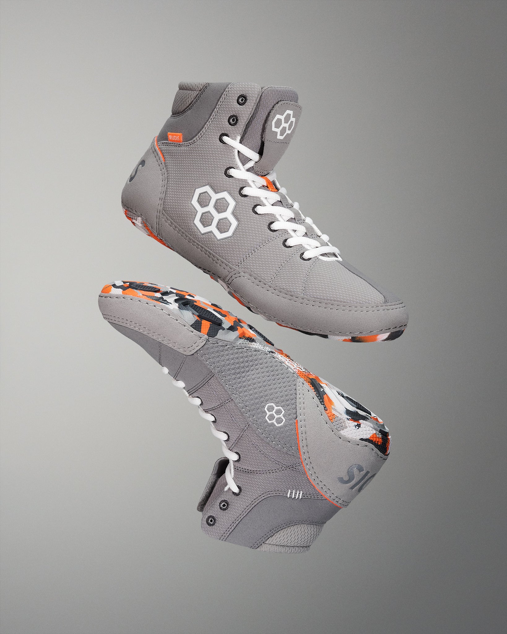 High-top athletic shoes feature a gray upper with vibrant orange and black accents, designed for style and support, showcased against a soft gradient background.