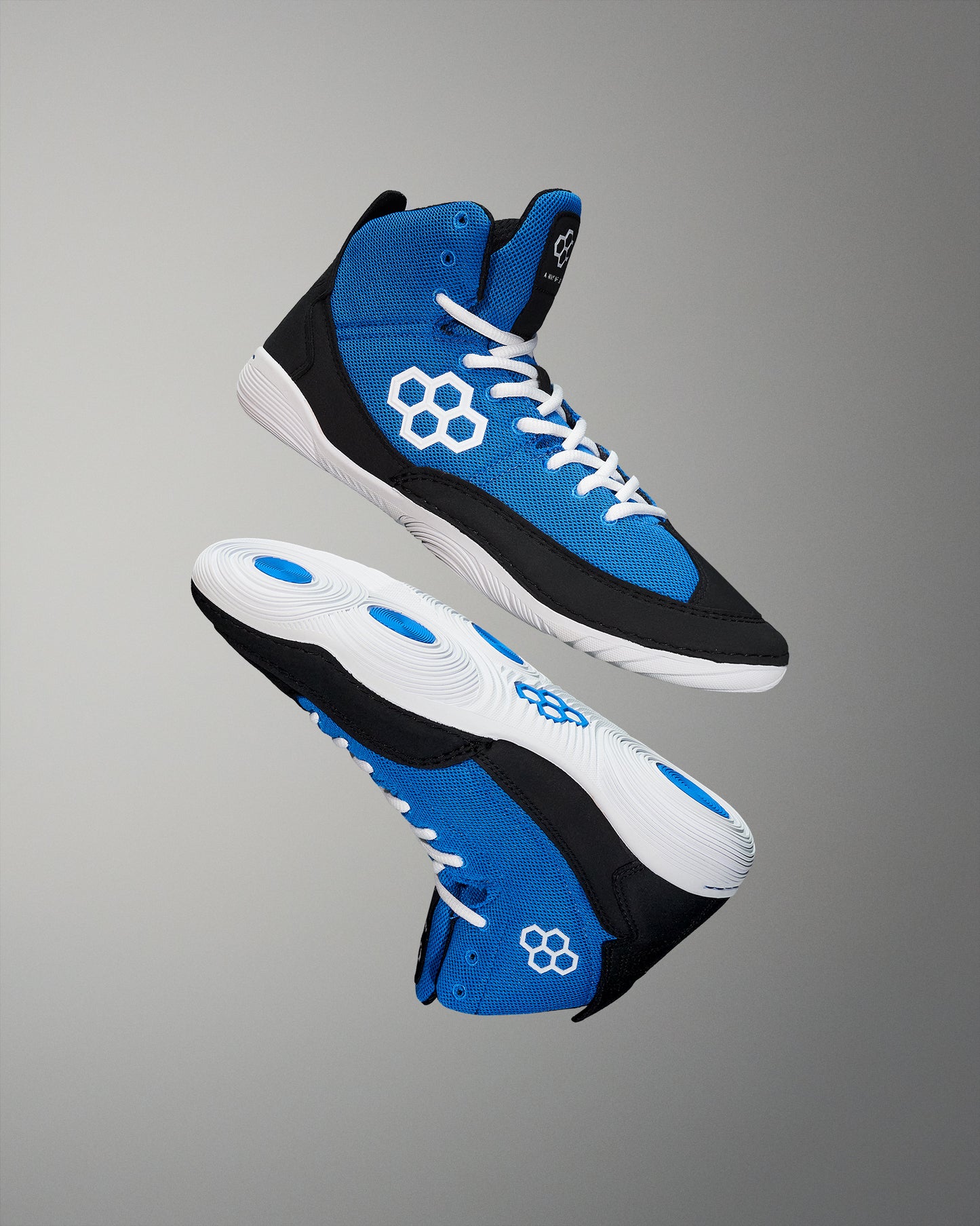 High-top athletic shoes feature a vibrant blue upper and black paneling, with white accents and a focus on traction, set against a neutral gray backdrop.