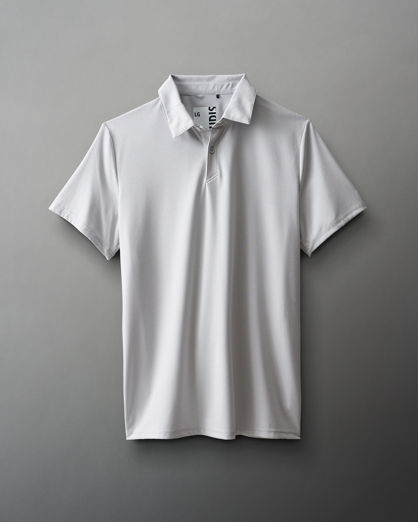 A plain white polo shirt with a classic design and three-button placket is showcased on a smooth gray background, emphasizing its versatility for casual or semi-formal wear.