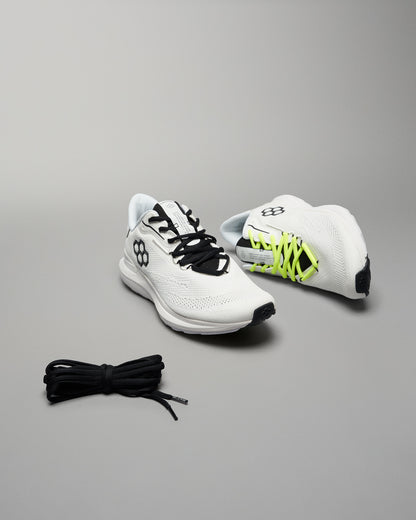 A pair of modern running shoes in white with contrasting black and neon yellow laces set against a neutral background featuring textured mesh uppers and a sleek design