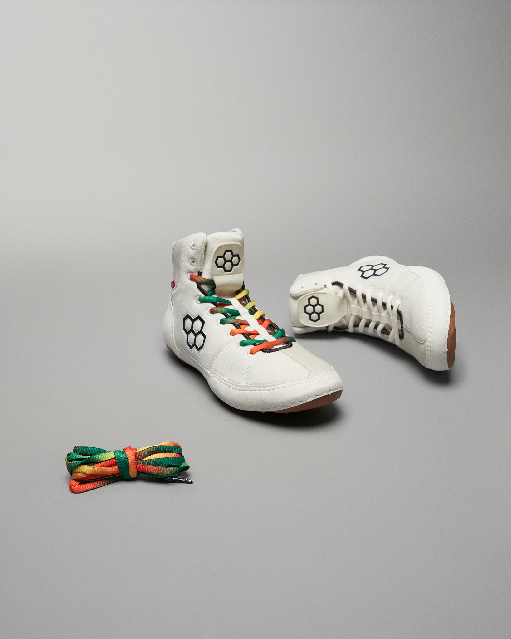 Stylish white high-top sneakers featuring multicolored laces and a distinctive logo accompanied by an additional pair of colorful laces