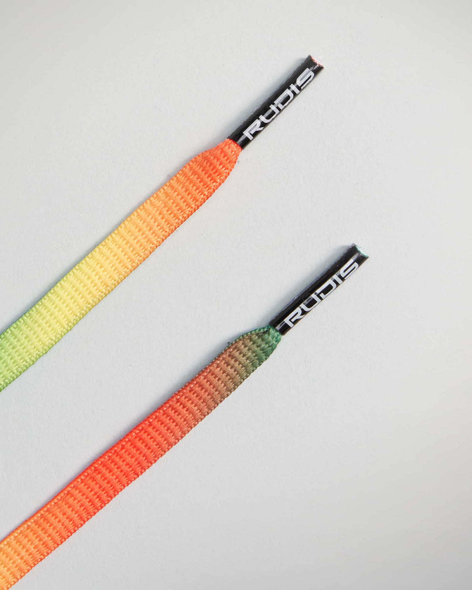 A pair of vibrant shoelaces featuring a gradient of colors from green to orange designed with a stylish finish and branded tips