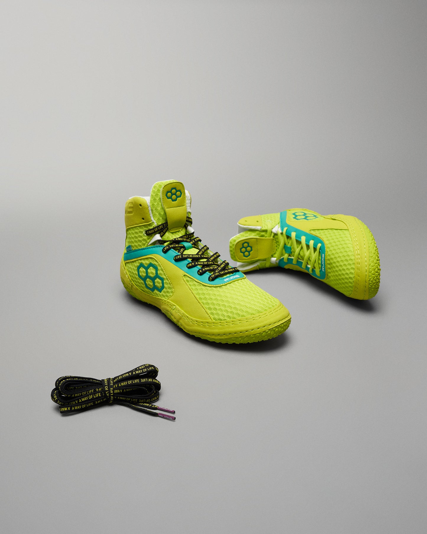 Bright yellow athletic shoes featuring a breathable mesh upper bold turquoise accents and unique patterned laces positioned with an extra set of laces alongside them