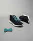 A pair of stylish black athletic shoes with turquoise laces and a matching lace bundle on a gray background