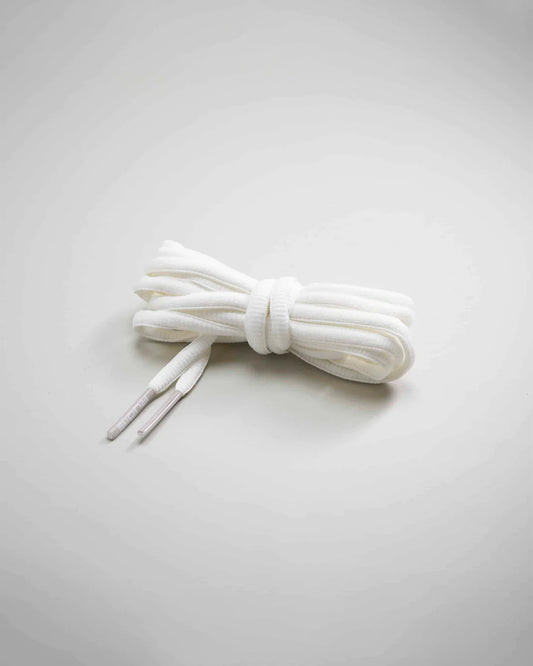 A neatly arranged bundle of white shoelaces with flat textured surface and plastic tips set against a soft gray background