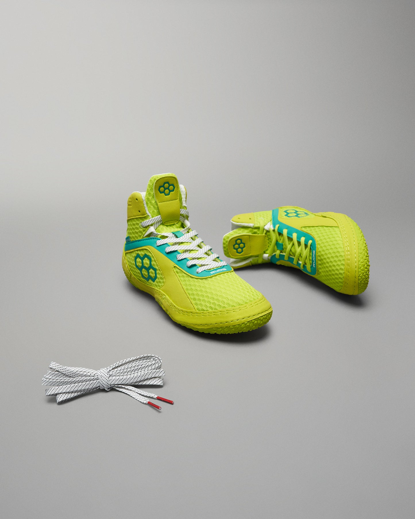 Bright yellow athletic shoes designed for performance featuring a breathable mesh upper and colorful accents with a lace accessory beside them