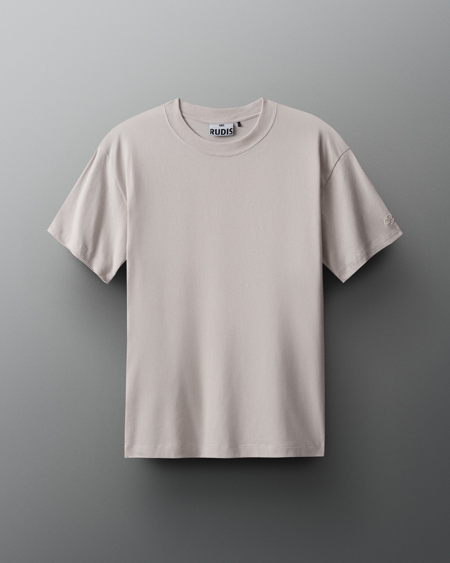 A light beige T-shirt with a round neckline and short sleeves is displayed against a muted gray background, showcasing a comfortable texture and subtle branding.