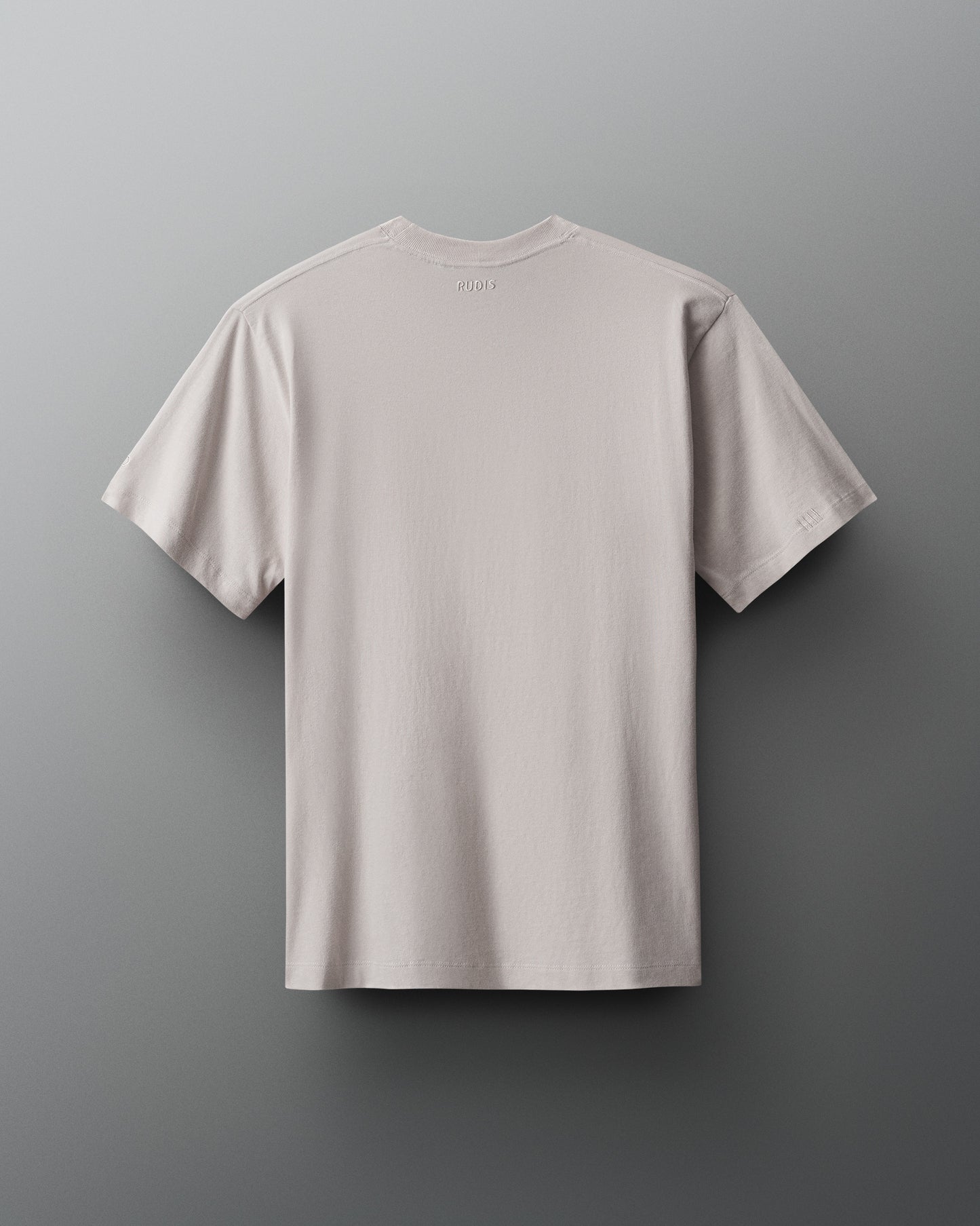 A minimalist light gray t-shirt is displayed flat against a gradient gray background, highlighting its simple design and textured fabric.