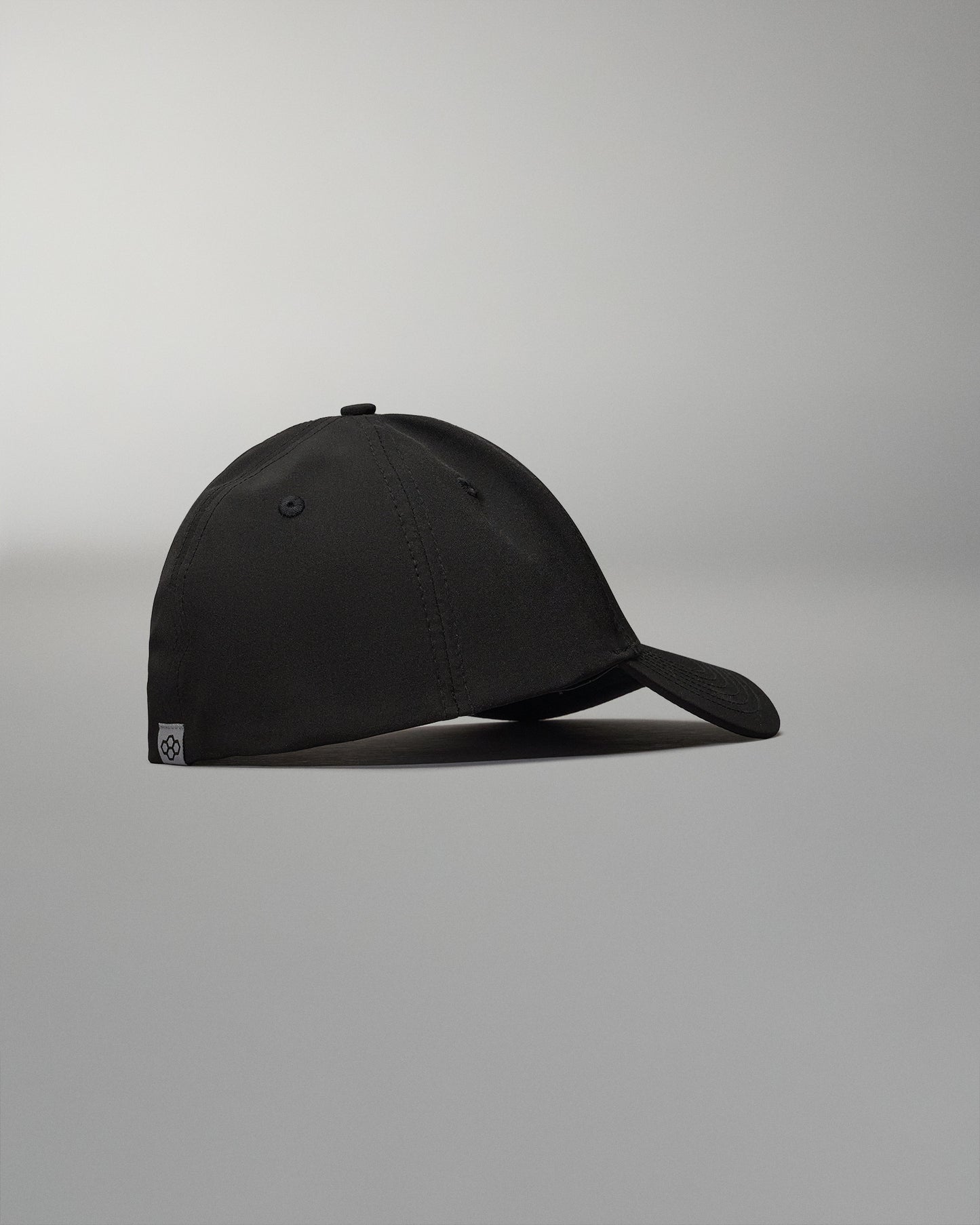 A sleek black cap is shown from the side featuring a curved visor and a simple design resting on a neutral background for emphasis