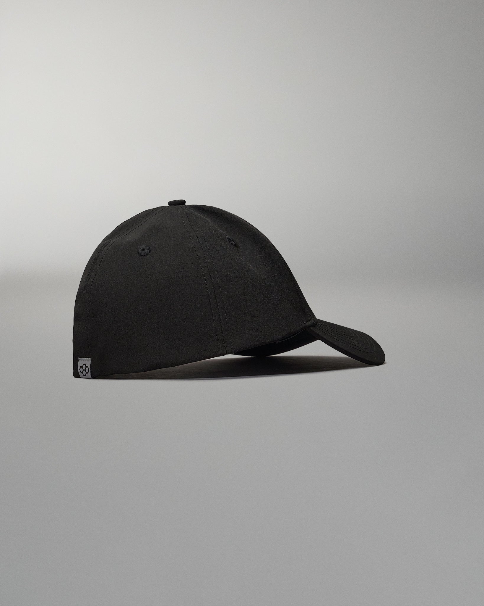 A sleek black cap displayed from a side angle featuring a curved brim and minimalist design