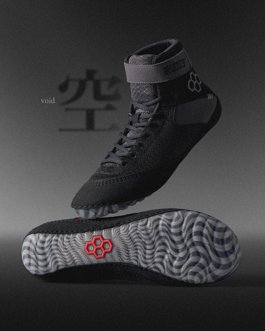 High-top athletic shoes showcase a black textured design with a patterned gray sole and red branding, combining functionality and style.