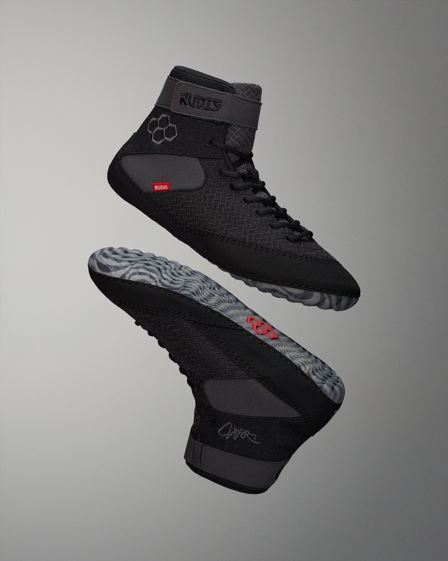 High-top athletic shoes showcase a black textured design with a patterned gray sole and red branding, combining functionality and style.