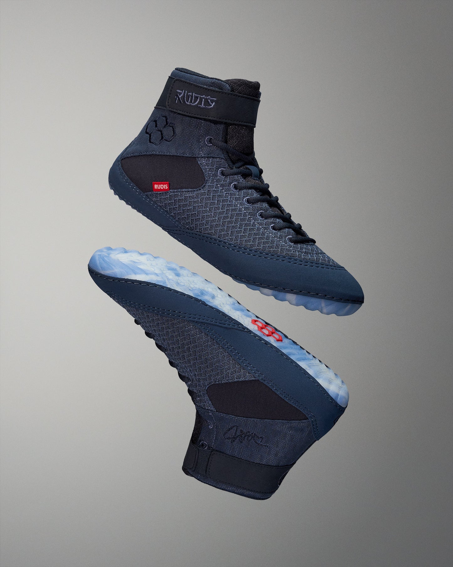 High-top wrestling shoes in a blue-black design with a textured upper and translucent sole, designed for performance, are presented against a smooth gradient background.