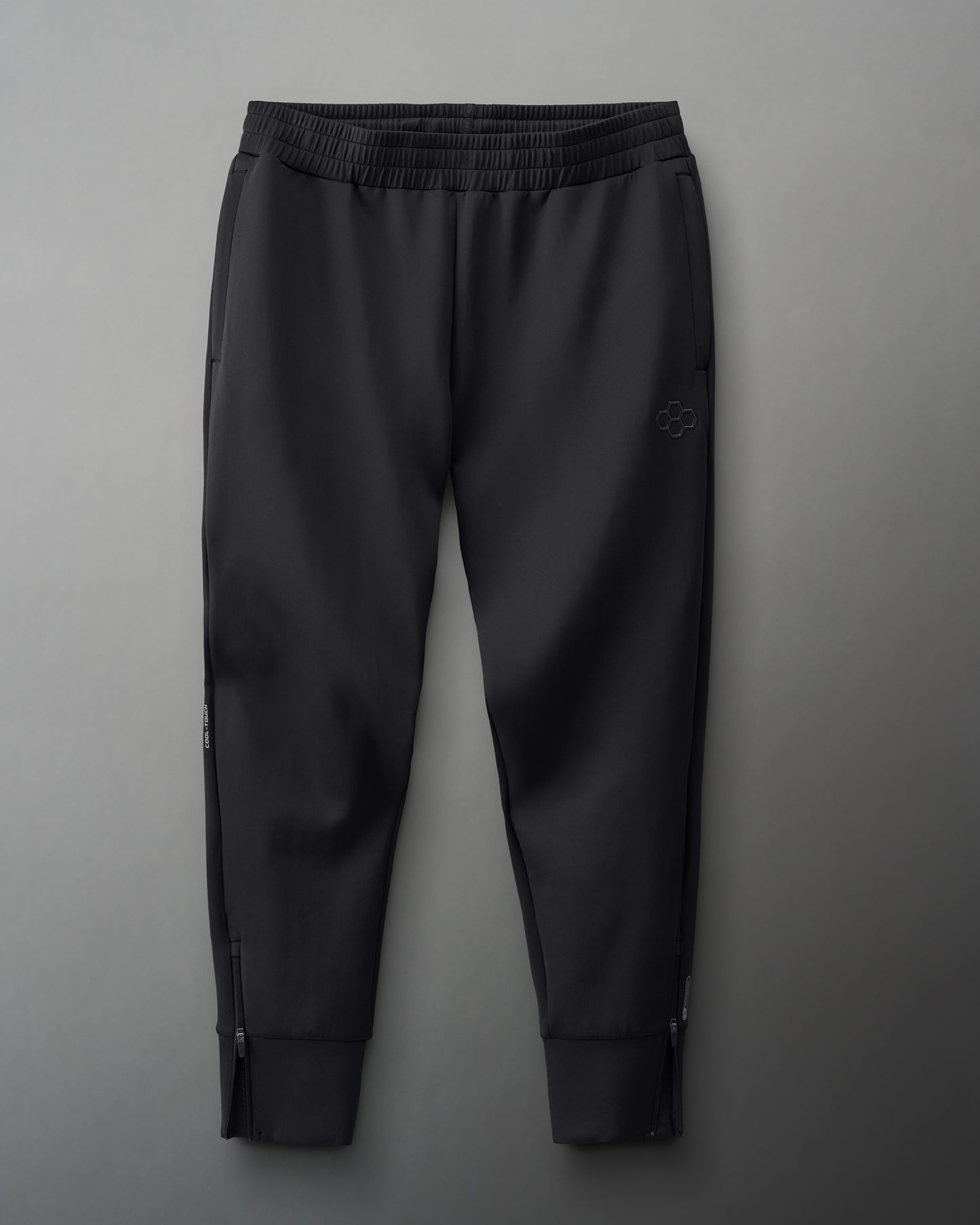 Black athletic pants with a ribbed waistband, zippered pockets, and tapered legs for a sleek, functional design.