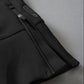 Black athletic shorts with a textured fabric and zippered pocket, featuring metallic zipper pull against a light gray background.