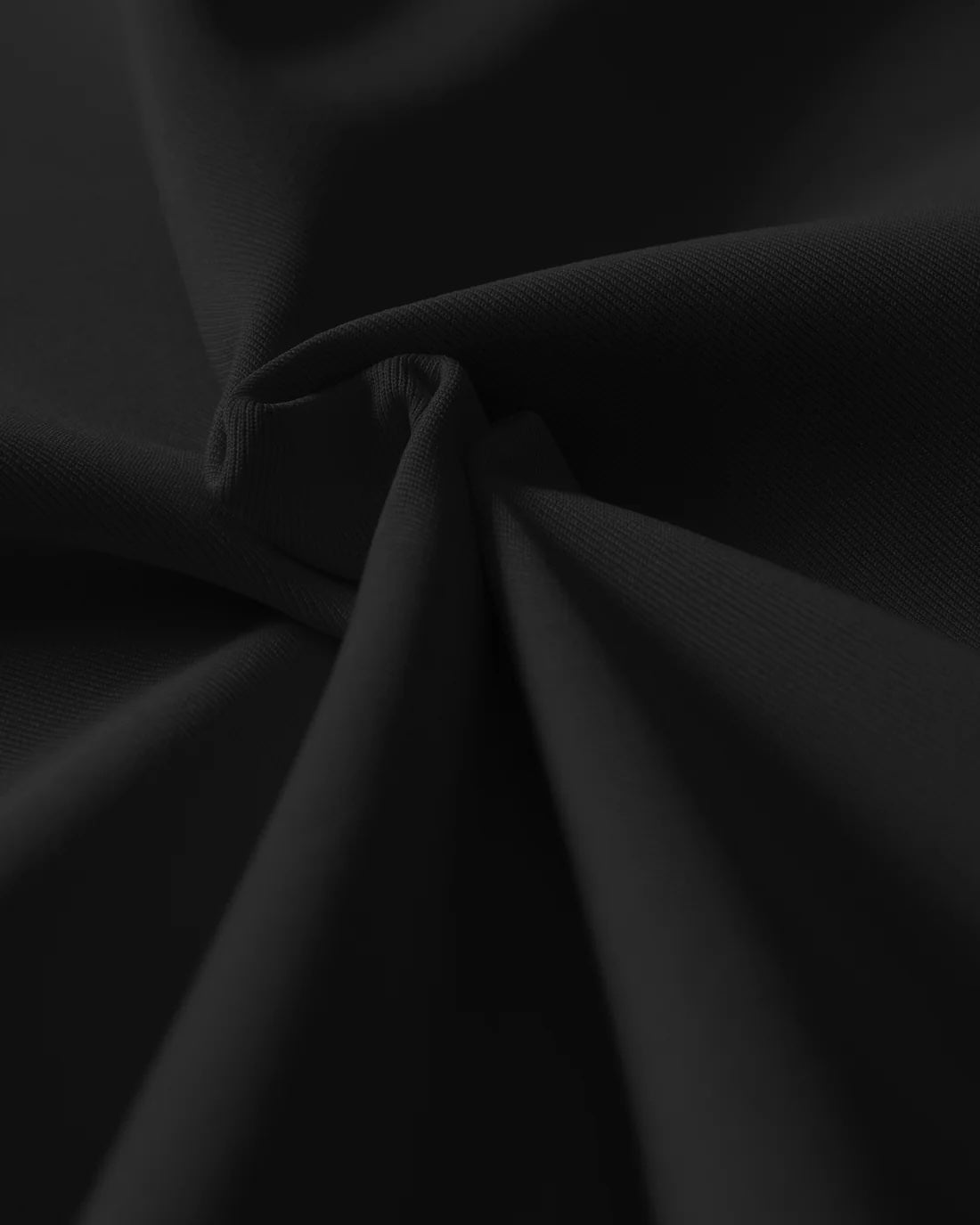 A close-up of black fabric reveals its smooth texture and gentle folds, emphasizing quality and versatility.