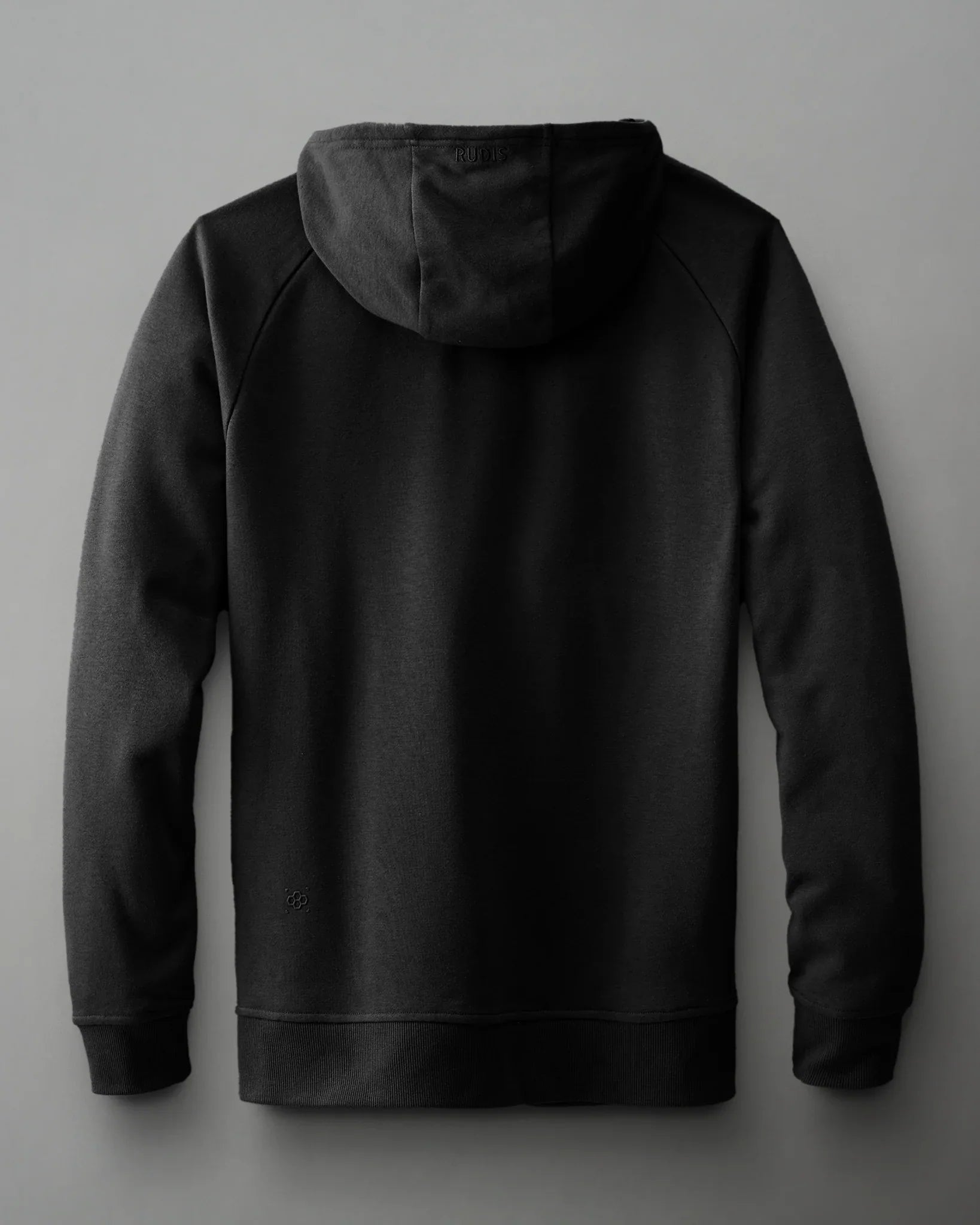 A black hoodie, showcasing a soft texture and ribbed cuffs, is displayed against a gray backdrop, emphasizing minimalist design and casual comfort.