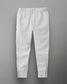 White athletic sweatpants with zippered pockets and ankle zippers for comfort and style, featuring a subtle logo on the left thigh.