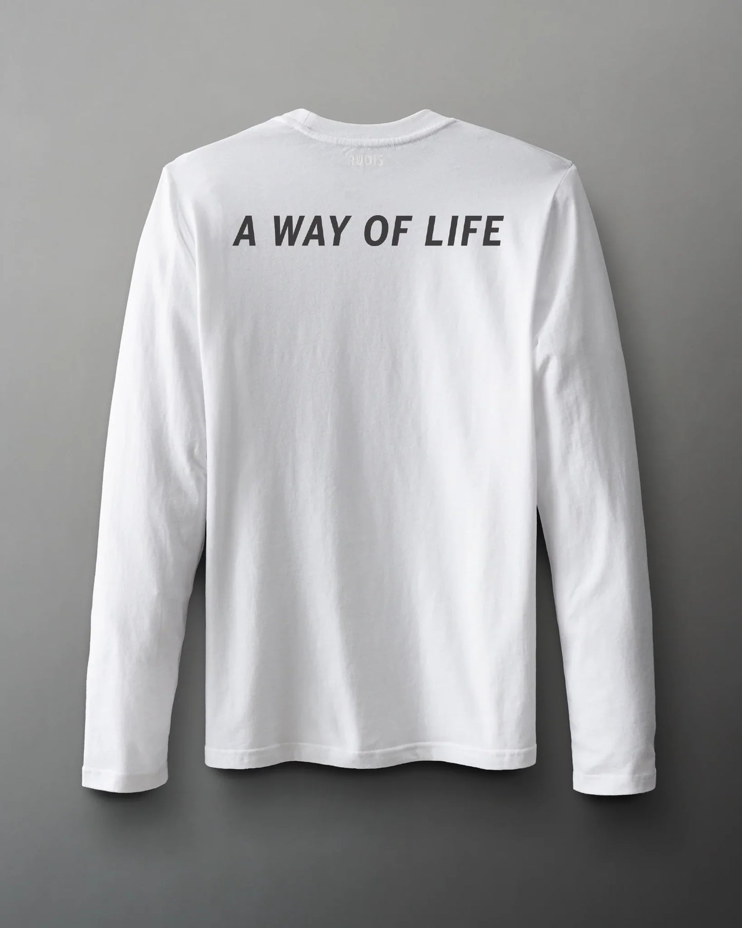 A long-sleeve white shirt with a relaxed fit prominently displays the phrase 'A WAY OF LIFE' in black on the back, set against a gray background.