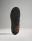 The sole of a black athletic shoe featuring a unique textured pattern and a distinctive copper emblem design