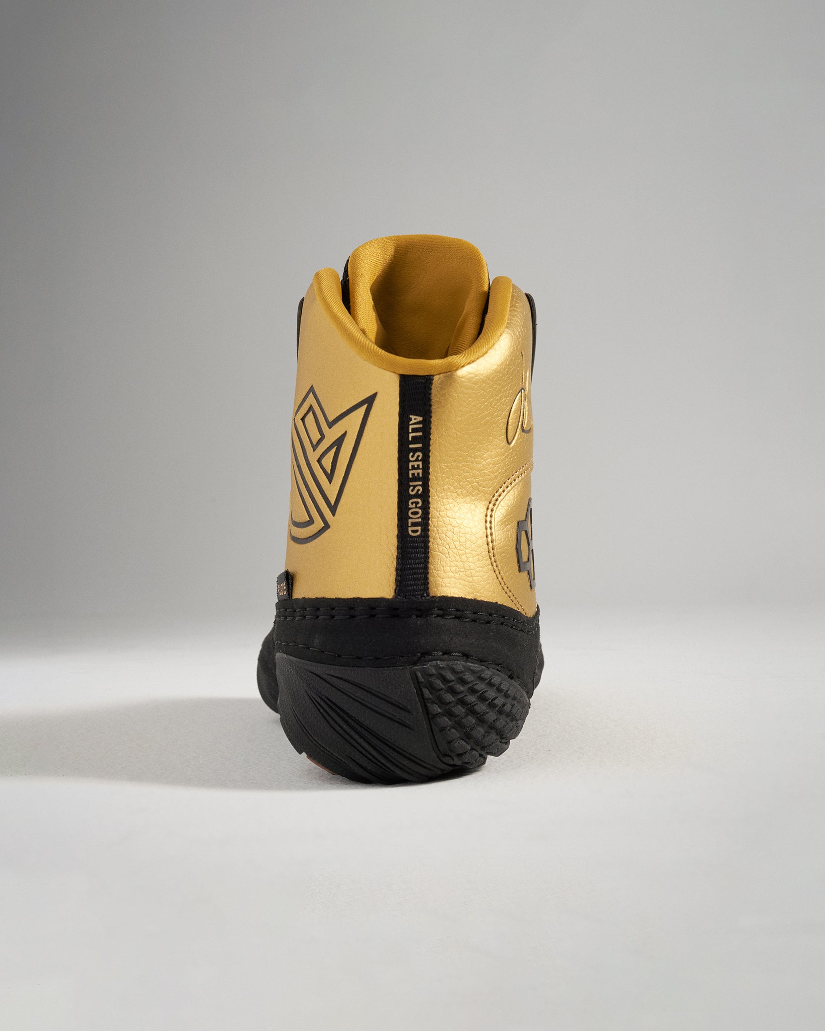 A stylish sneaker with a glossy gold upper and black accents featuring distinctive branding and a textured sole for grip