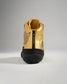 A stylish sneaker with a glossy gold upper and black accents featuring distinctive branding and a textured sole for grip