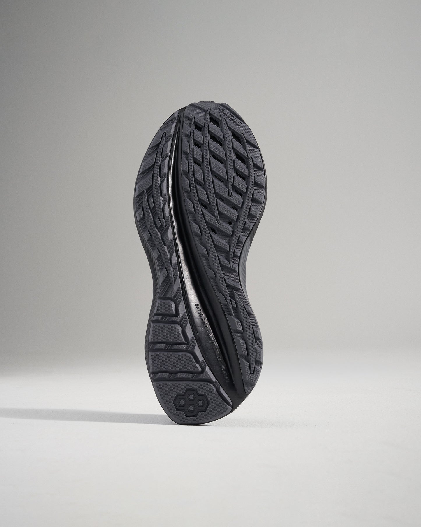 Underside view of a black athletic shoe showcasing its textured sole designed for traction and support during physical activities